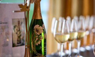 Eine elegante Flasche Sekt in einem stilvollen Display, umgeben von Gläsern. Der Hintergrund zeigt einen warmen, einladenden Raum. | © Hotel Birkenhöhe | Annette Sandner