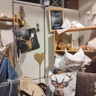 A cozy room with various cushions and decorative items. On a shelf, there are items with animal motifs and wooden accessories. | © Abler Mittelberg | N. Lughammer