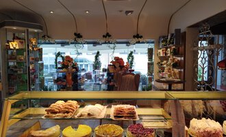 A cozy bakery with a selection of sweet and savory baked goods. In the background, you can see tables and chairs for guests. | © Kleinwalsertal Tourismus | N. Lughammer