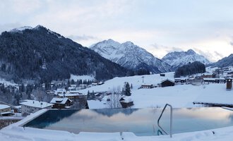 Ein schöner Blick auf schneebedeckte Berge und ein Infinity-Pool. Die ruhige winterliche Landschaft strahlt Frieden aus. | © Hotel Erlebach | Kristin Winter
