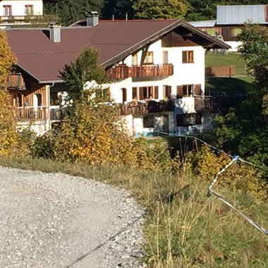 An idyllic house amidst colorful autumn leaves. The garden is well-maintained and the building has a traditional Alpine style. | © Gasthof Café Alpenwald | Thorsten Alpenwald