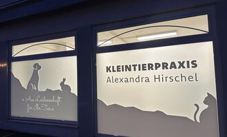A veterinary practice named "KLEINTIERPRAXIS Alexandra Hirschel". The windows display silhouettes of dog, cat, and rabbit.