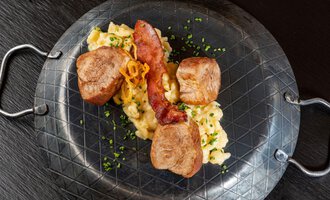Ein leckeres Gericht mit zartem Fleisch, Rührei und knusprigem Speck, serviert auf einem stilvollen Teller. Die Zutaten sind mit frischen Kräutern garniert. | © Hotel Alte Krone
