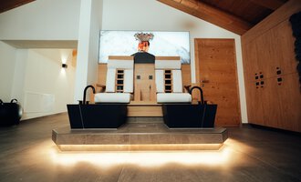 A modern wellness area with two footbath areas and a stylish wood paneling. The room is bright and inviting, ideal for relaxing.