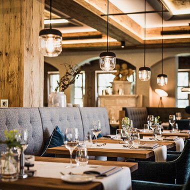 Ein stilvolles Restaurant mit eleganten Tischen und bequemen Sitzplätzen. Die gemütliche Atmosphäre wird durch sanfte Beleuchtung und natürliche Materialien hervorgehoben. | © Verwöhn- & Wellnesshotel Walserhof| Aileen Melucci