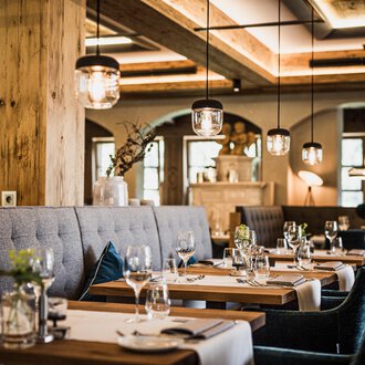 Ein stilvolles Restaurant mit eleganten Tischen und bequemen Sitzplätzen. Die gemütliche Atmosphäre wird durch sanfte Beleuchtung und natürliche Materialien hervorgehoben. | © Verwöhn- & Wellnesshotel Walserhof| Aileen Melucci
