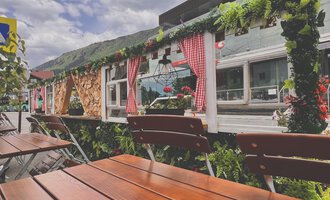 Ein gemütliches Café mit Pflanzen und Blumen dekoriert. Die Außenterrasse bietet hölzerne Tische und eine einladende Atmosphäre. | © Riezlern Eck | Sead Sulejmani