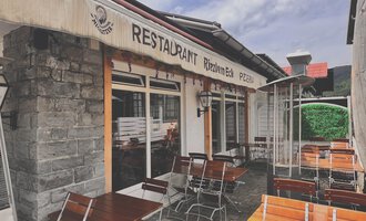 Ein gemütliches Restaurant mit Tischen im Freien und einer einladenden Atmosphäre. Die Fassade ist aus Stein mit einem markanten Schild. | © Riezlern Eck | Sead Sulejmani