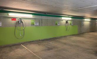 A modern underground parking garage with electric charging points. The walls are painted green and the lighting is bright. | © Naturhotel Chesa Valisa Hirschegg