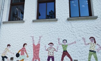 A colorful mural depicts children in various playing positions. They look cheerful, friendly, and lively. | © Kleinwalsertal Tourismus | N. Lughammer