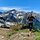 Woman hiking in the mountains with snow-capped peaks, carrying a backpack and trekking poles on a sunny day. | © Kleinwalsertal Tourismus eGen