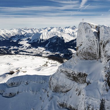 Mountain landscape with snow-covered peaks and rocks, overlooking a winter scene with mountains in the background. | © Kleinwalsertal Tourismus eGen • Photographer: Bastian Morell