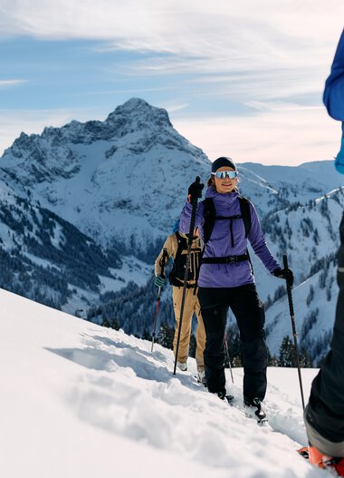 Group of skitourers trekking through snowy mountain landscape in Kleinwalsertal, equipped with backpacks and ski poles. | © Kleinwalsertal Tourismus eGen • Photographer: Oliver Farys