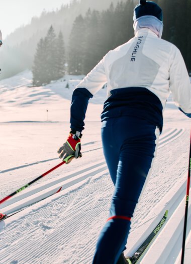 Two cross-country skiers on the Schwarzwasserloipe in Kleinwalsertal amid snowy scenery and mountains. | © Kleinwalsertal Tourismus eGen • Photographer: Oliver Farys