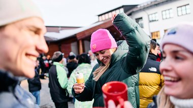 Happy people at the snowman gathering in Kleinwalsertal, some drinking hot drinks. | © Kleinwalsertal Tourismus eGen • Photographer: Oliver Farys