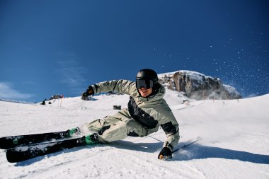 Skifahrer bei einem künstlerischen Sturz im Schnee auf einer Skipiste unter einem blauen Himmel. | © Kleinwalsertal Tourismus eGen • Fotograf: Oliver Farys