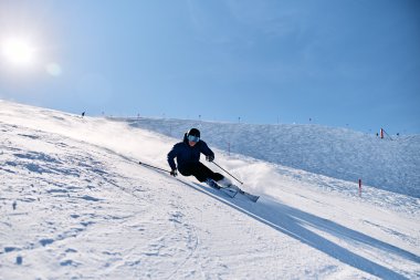 Ein Skifahrer in dunkler Kleidung und mit Skibrille fährt an steiler Piste im Schneeterrain ab. | © Kleinwalsertal Tourismus eGen • Fotograf: Oliver Farys