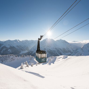 Gondelbahn im Wintertraum mit verschneiten Bergen und klarer Himmelssonne im Hintergrund. | © Oberstdorf · Kleinwalsertal Bergbahnen