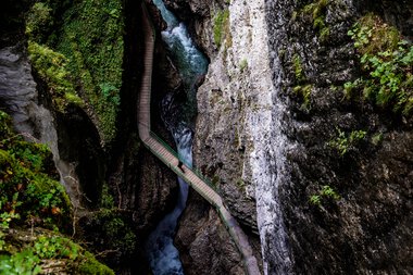 Blick vom Zwingsteig in die Breitachklamm im Sommer, enges Tal mit Wasser und Felsen, Umgeben von grüner Vegetation. | © Kleinwalsertal Tourismus eGen • Breitachklamm • Fotograf: Domink Berchtold