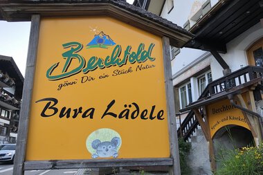 Signboard of Bura Lädle, a local shop, with the name and a mouse logo, in Berchtold, Austria. | © Kleinwalsertal Tourismus eGen • Berchtolds Bura Lädele