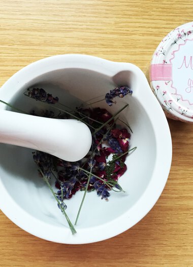 A mortar with dried lavender flowers on a wooden surface, next to a small lid with the inscription 'Made with Love'. | © Kleinwalsertal Tourismus eGen