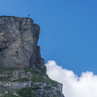 Cliff at the summit of Ifen with cross, under a blue sky with clouds in summer. | © Kleinwalsertal Tourismus eGen • Photographer: Steffen Berschin