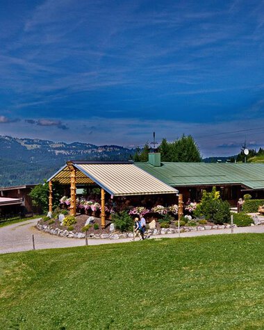 Bergstüble in Kleinwalsertal with green meadow, blue sky, and surrounding mountains, in summer on a clear day. | © Kleinwalsertal Tourismus eGen